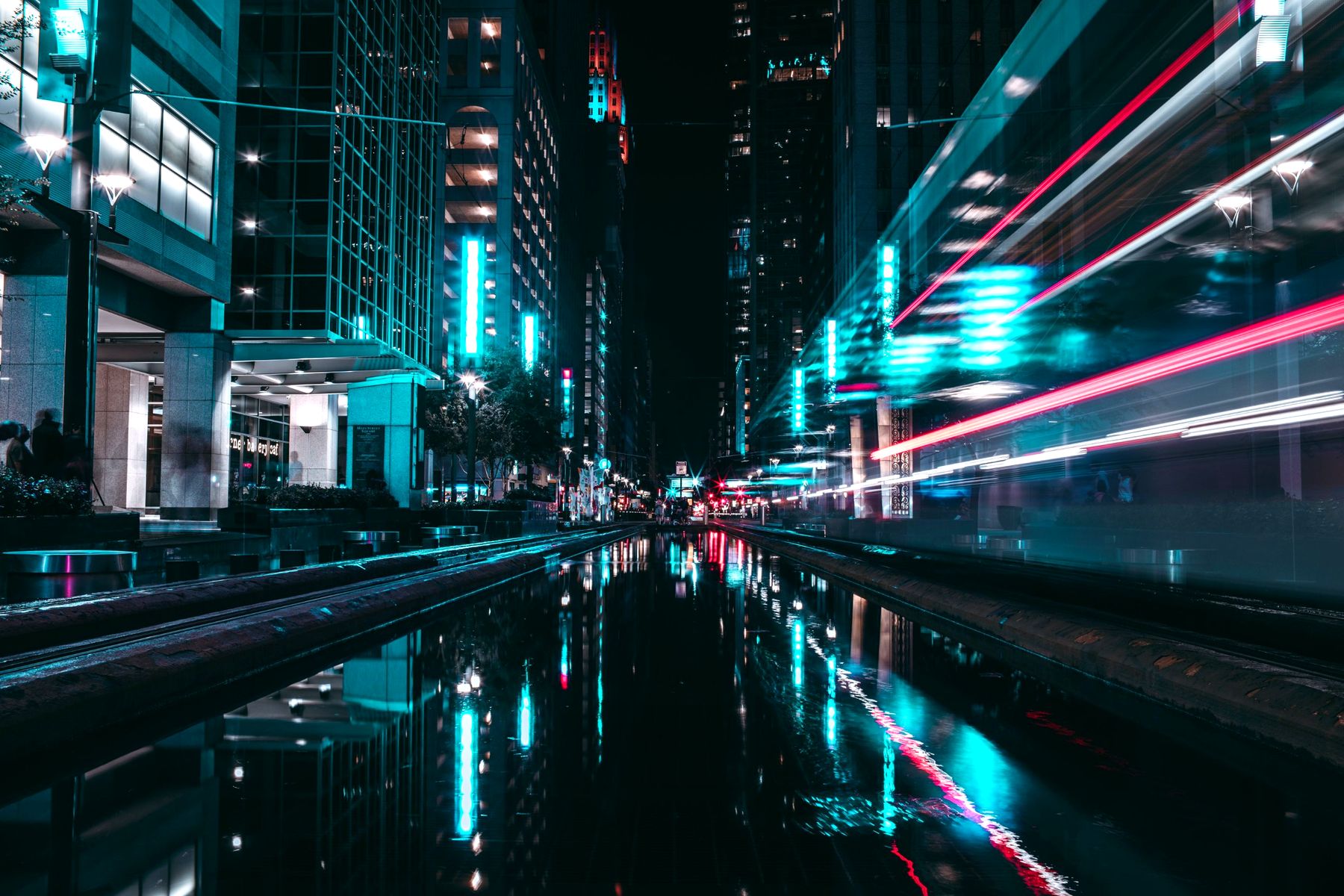 Main Street in downtown Houston at night, with light trails reflected in water